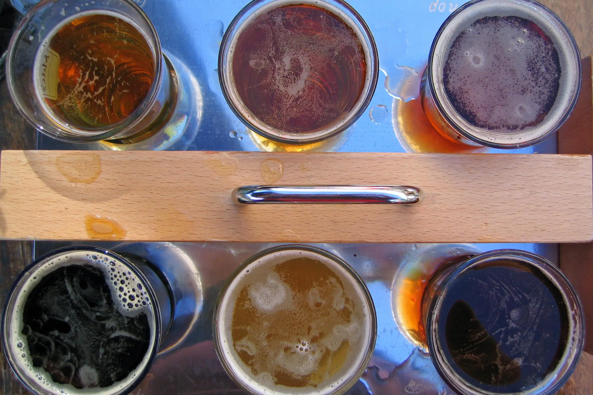 Ein hölzerner Bierträger mit sechs Gläsern unterschiedlicher Biersorten für ein Tasting von Brausirup-Bieren