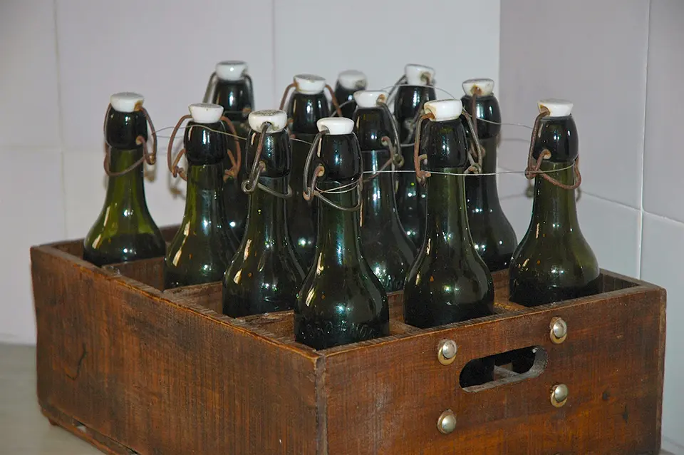 Ein rustikaler Holzkasten gefüllt mit leeren Bügelflaschen für die Abfüllung von selbst gebrautem belgischem Witbier.