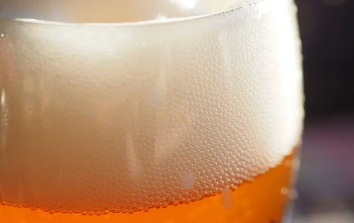 Nahaufnahme von feinem, dichtem Bierschaum in einem Glas als Ergebnis einer erfolgreichen Zwangskarbonisierung beim Brauen.